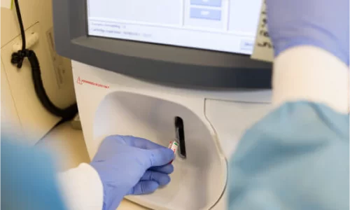 physician inserting blood sample into flow cytometry machine